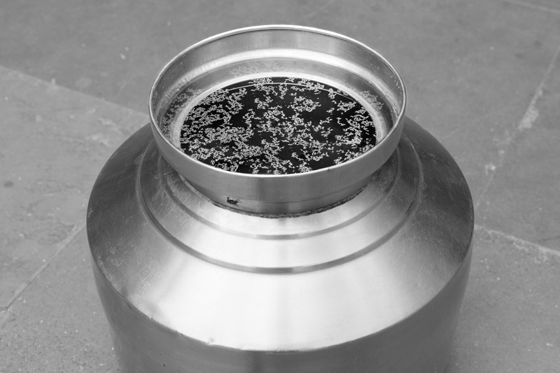 Industry and Violation of Human Right to Water - Drinking water from the tanker stored in a pot, showing a fat greasy layer on top within an hour - in Bichhadi, Udaipur district, Rajasthan